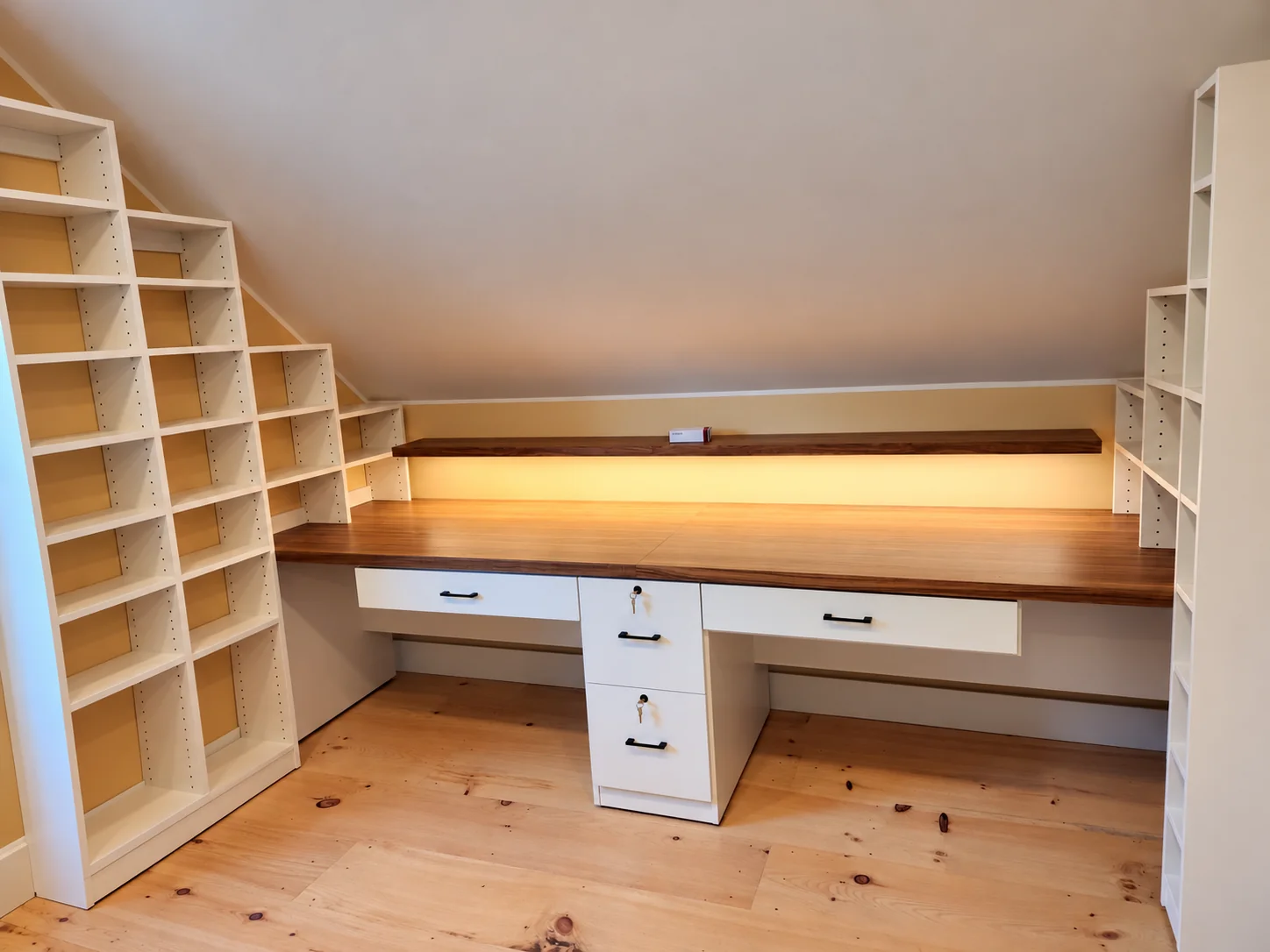 Built-in attic desk with a wood countertop, four drawers, open shelves and warm integrated lighting