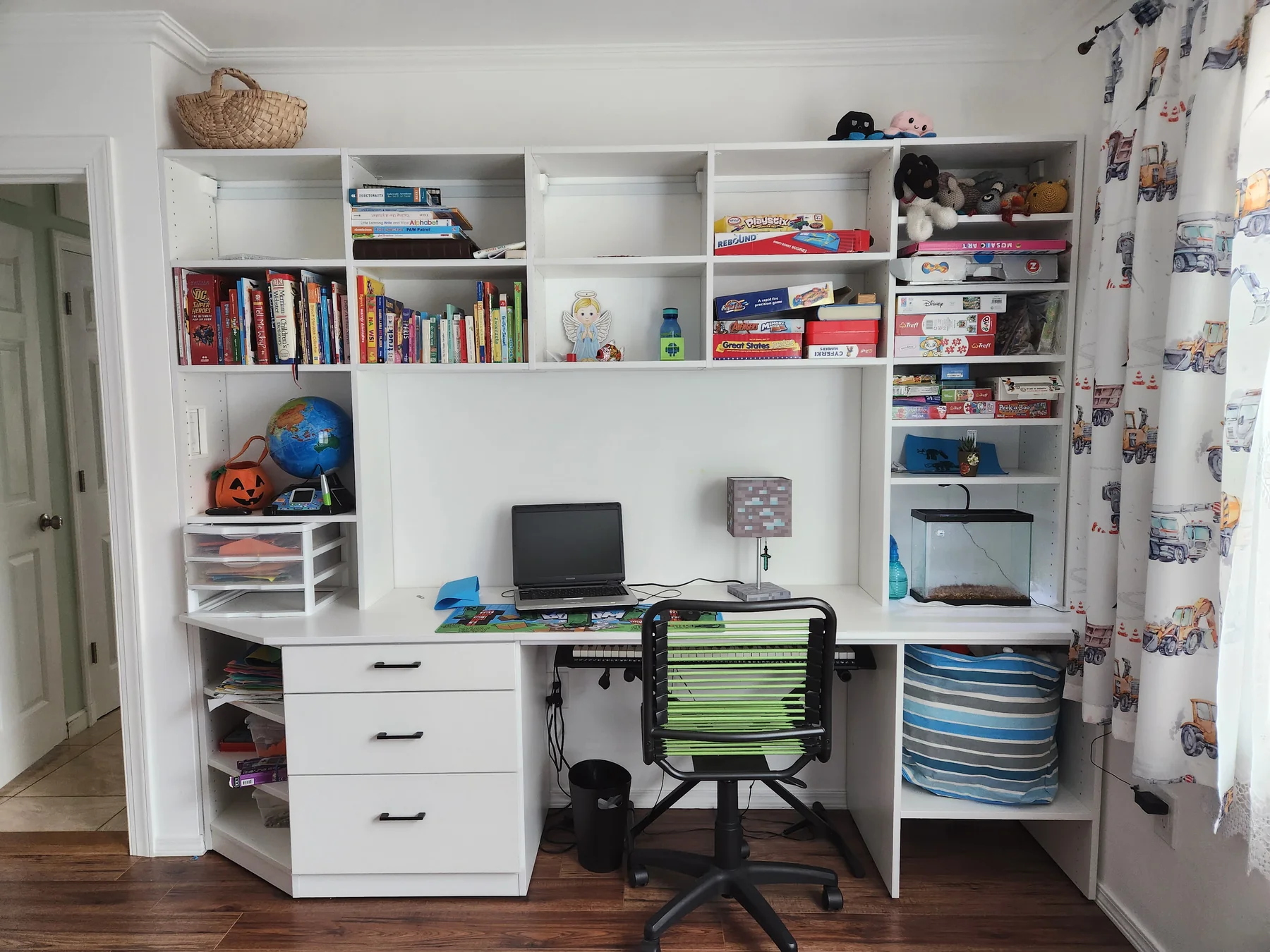 White built-in study with a desk, drawers, book shelves and a green desk chair