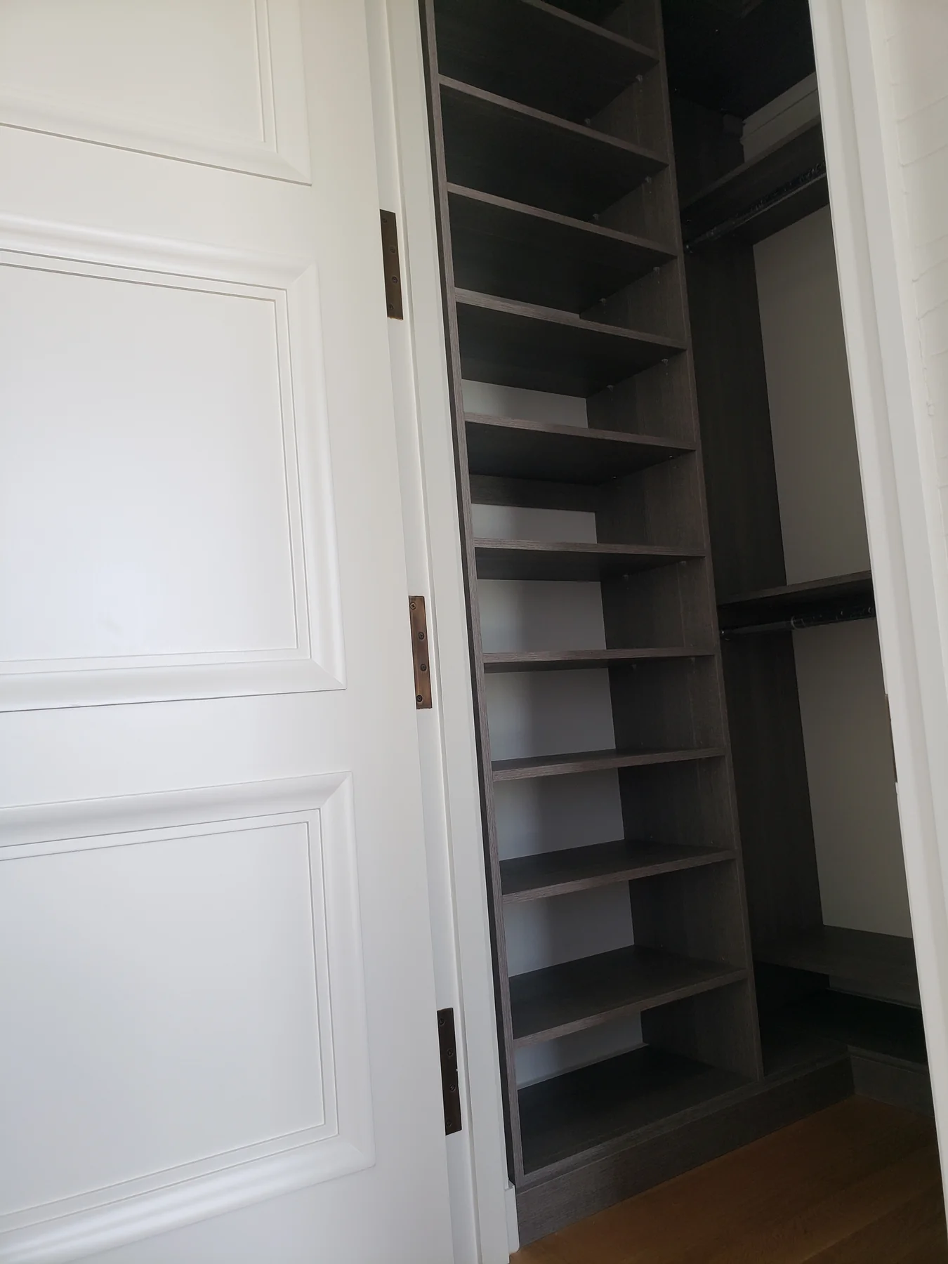 Dark gray reach-in closet with a tall adjustable shelf tower and hanging sections