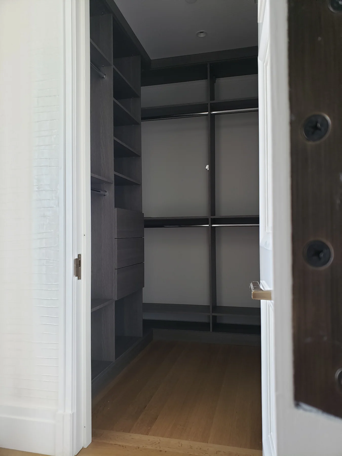 Open doorway view of a compact gray closet with double hanging rails