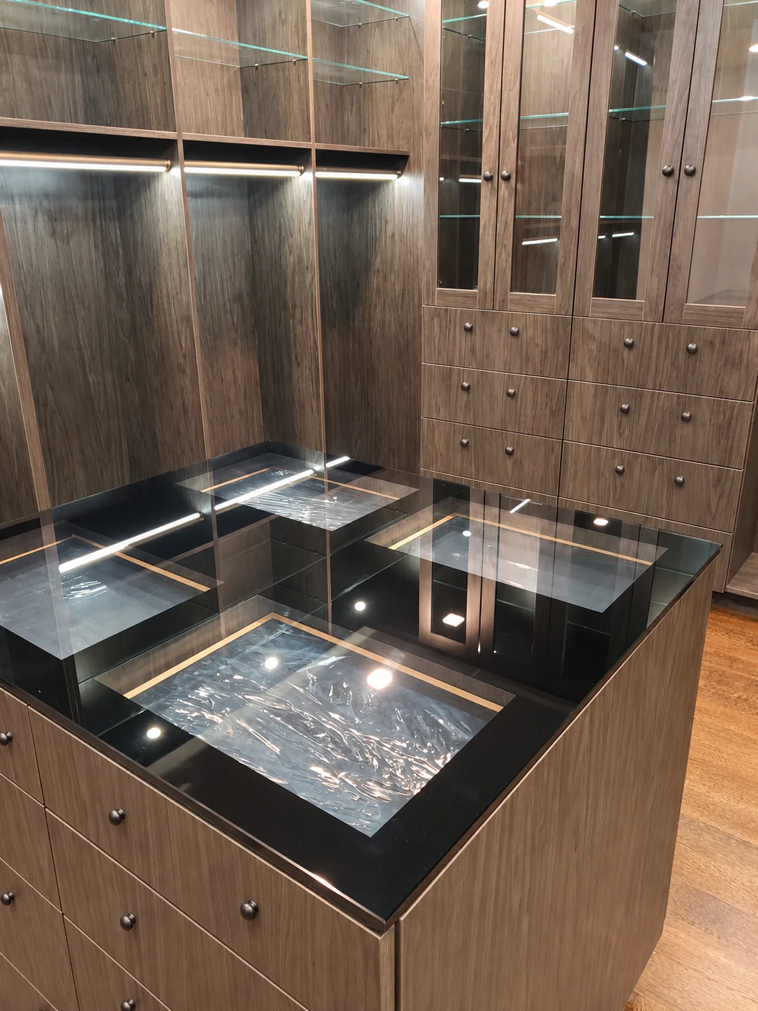 Glass display top on a dark wood-grain closet island with drawer storage behind