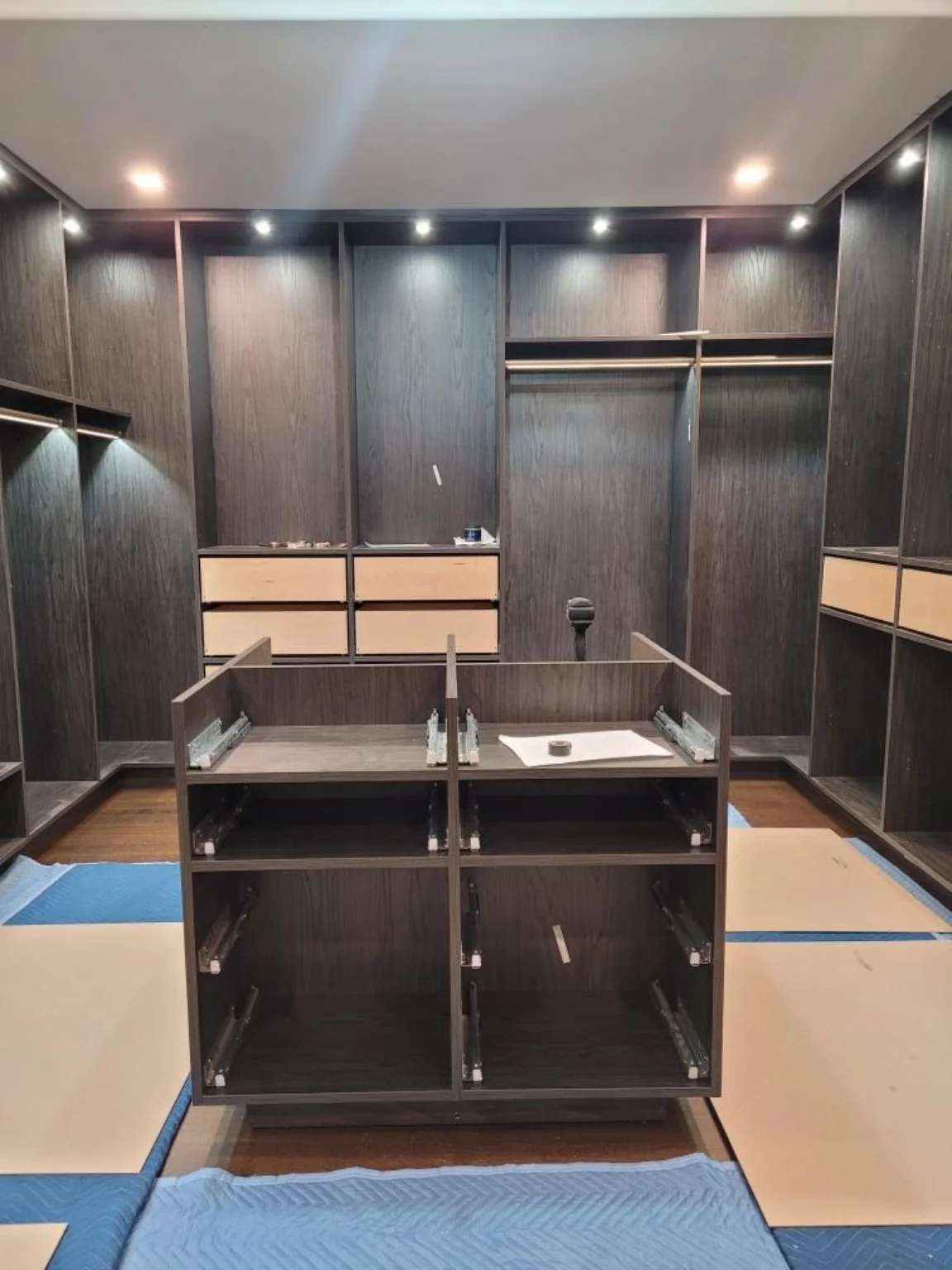 During installation: assembling the central closet island with exposed drawer slides and unfinished wall drawer storage