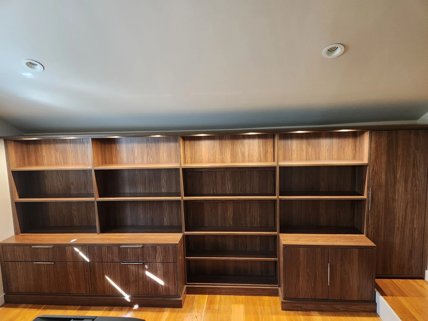 Full view of a wall-to-wall library with stepped lower cabinets and central open shelves