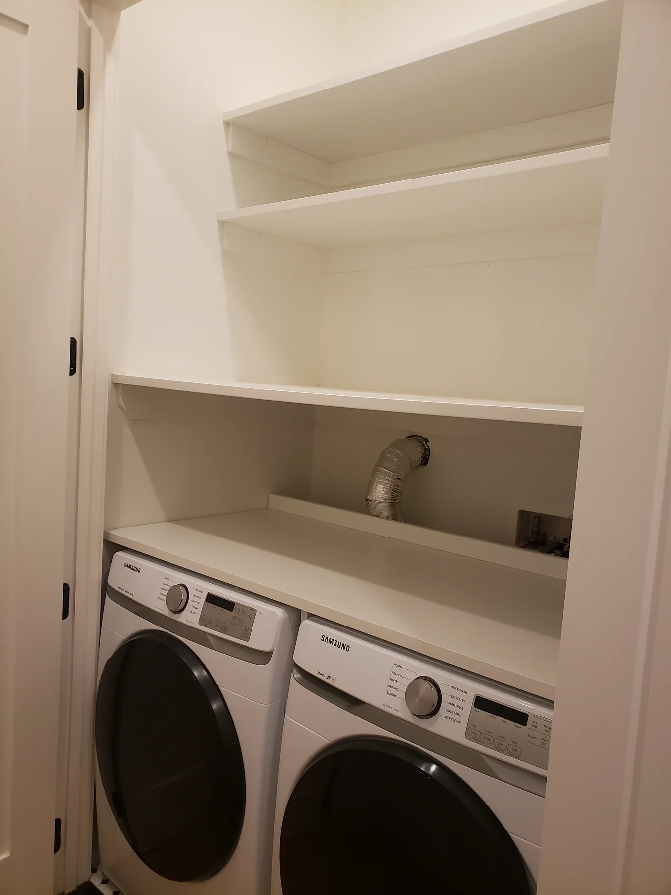 White laundry shelving above a washer, dryer and compact utility sink