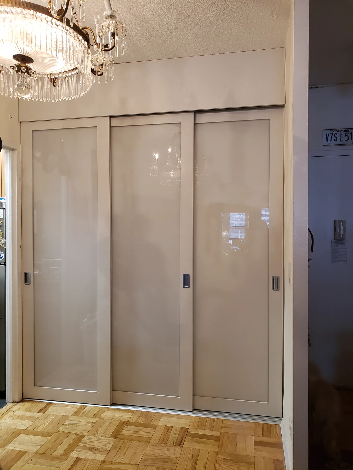 Wall-to-wall wardrobe with two glossy sliding doors and upper storage