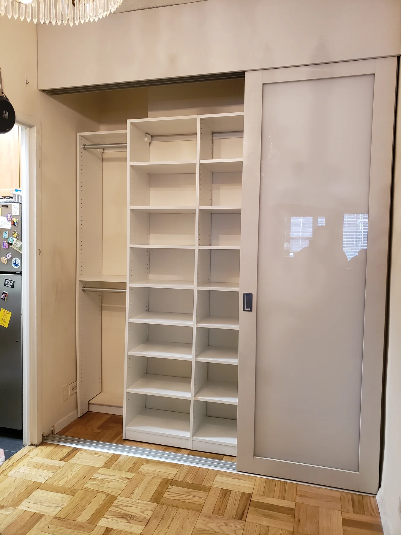 Sliding wardrobe door open to reveal a tall tower of adjustable shelves