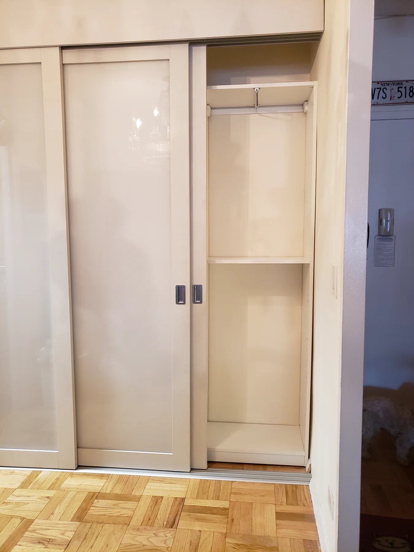 Open hanging section behind a glossy sliding wardrobe door