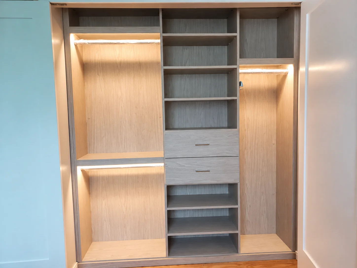 Two-tone wardrobe with illuminated hanging sections, central shelves and two drawers