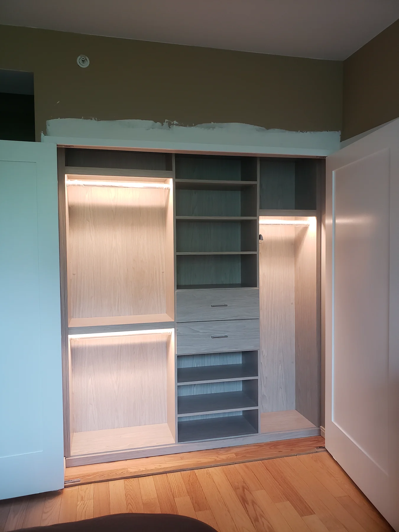 Full view of a reach-in wardrobe with wood-finish back panels and gray central storage