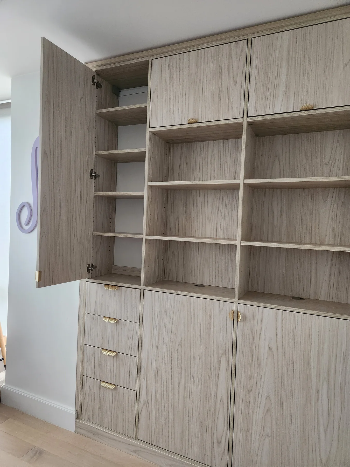 Open cabinet door reveals adjustable shelves beside the central display shelving