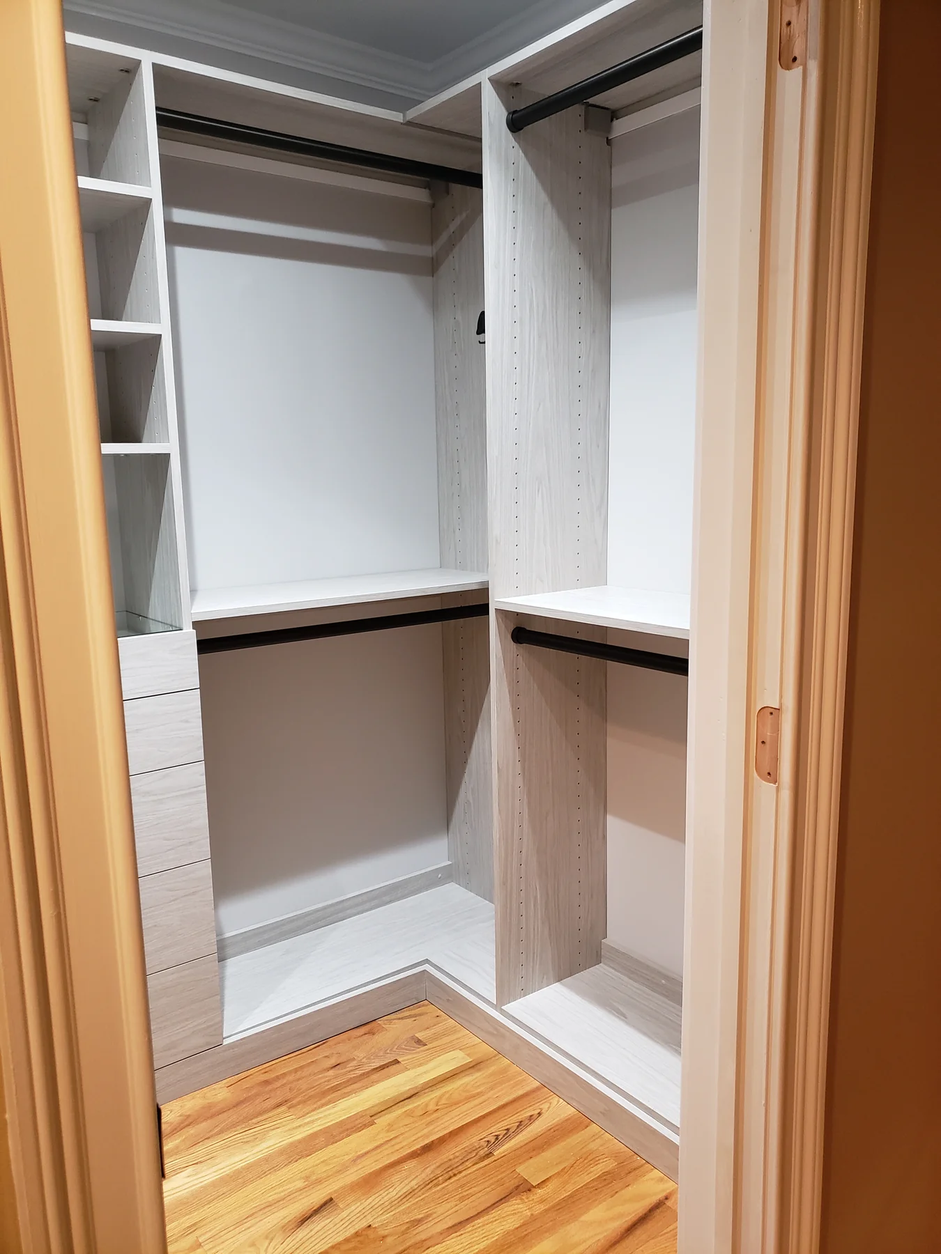 Open closet doorway showing light wood-grain partitions and double hanging rails