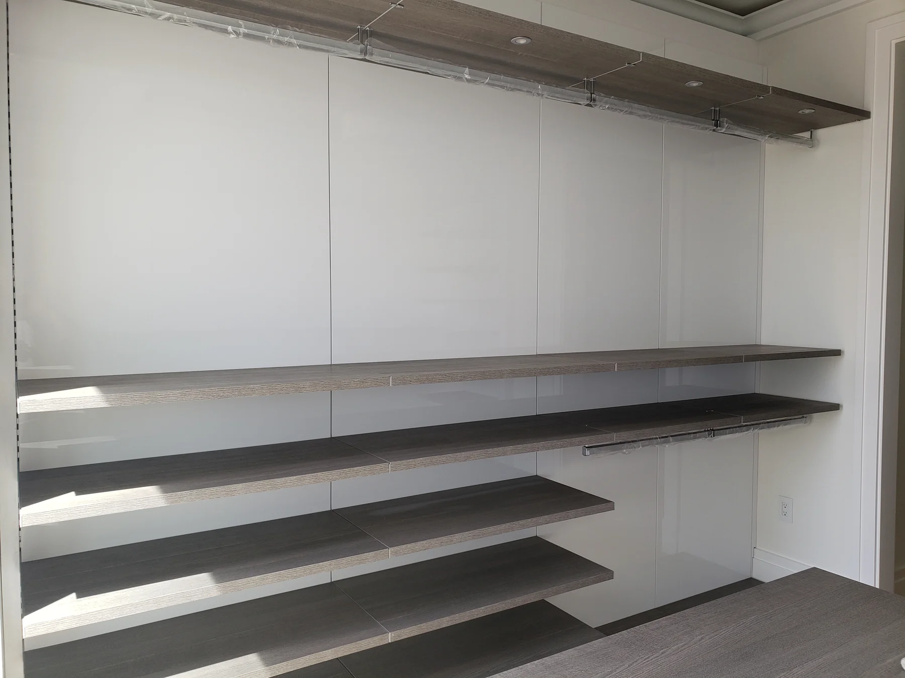 Floating shelves and metal hanging rails against glossy white closet back panels