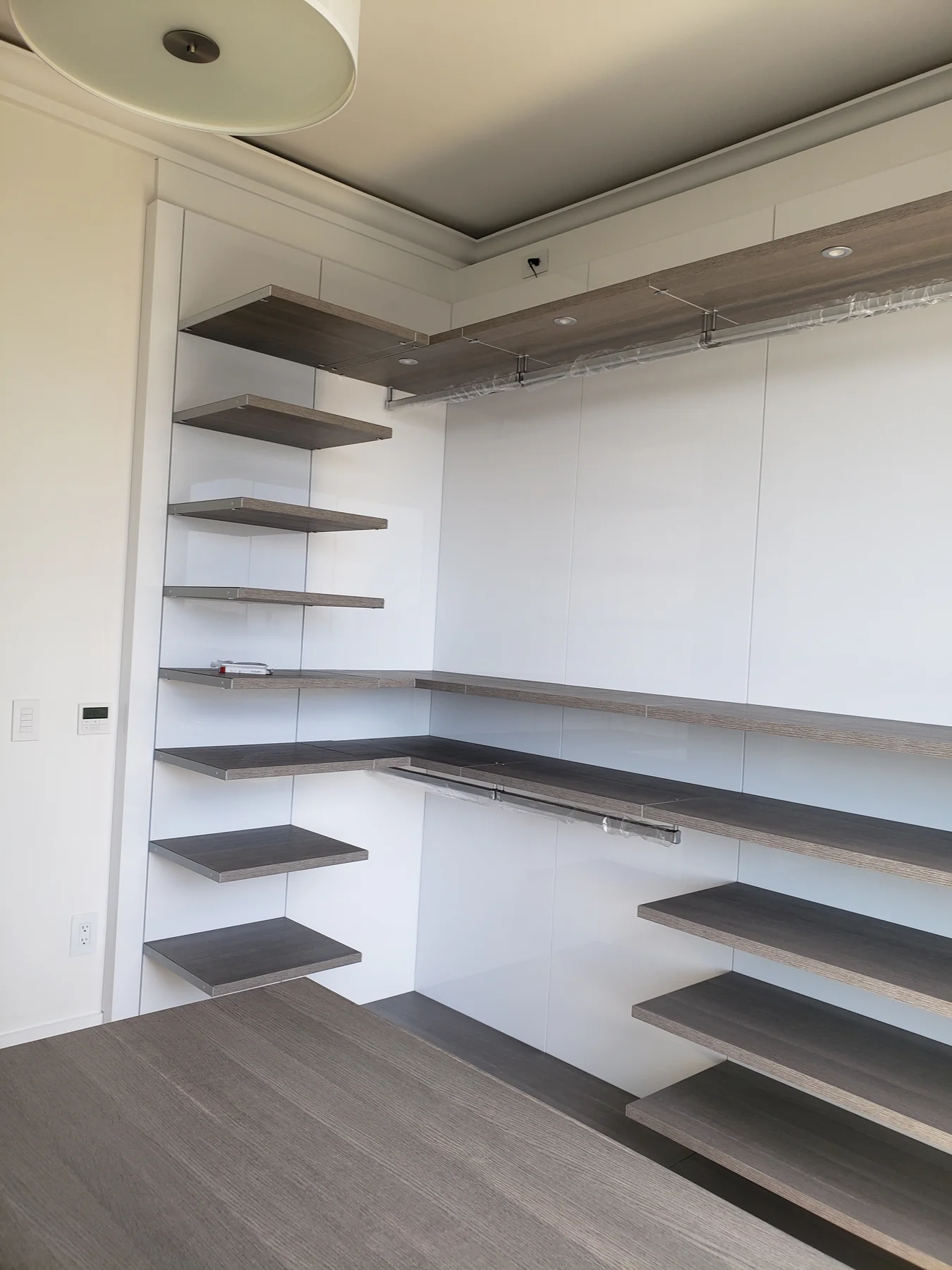 Corner closet layout with floating shelves, hanging rails and upper storage