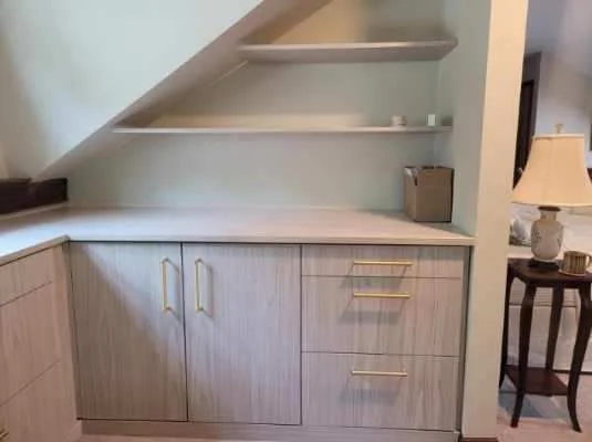 Custom attic cabinet with brass-colored handles and open shelves following the slope of the ceiling
