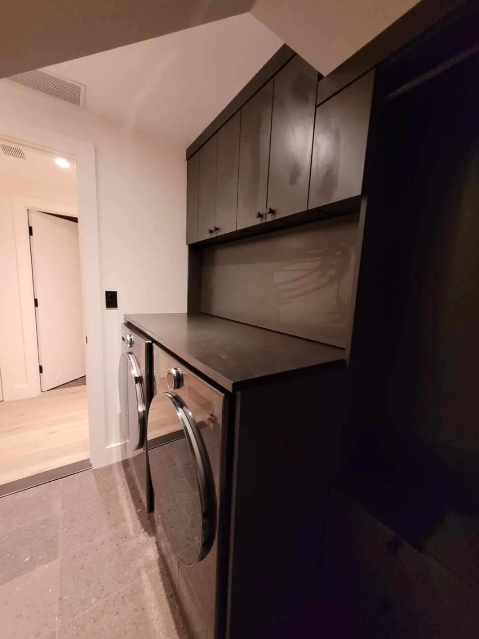 Angled view of the laundry worktop, upper cupboards and tall side storage fitted beneath a sloped ceiling