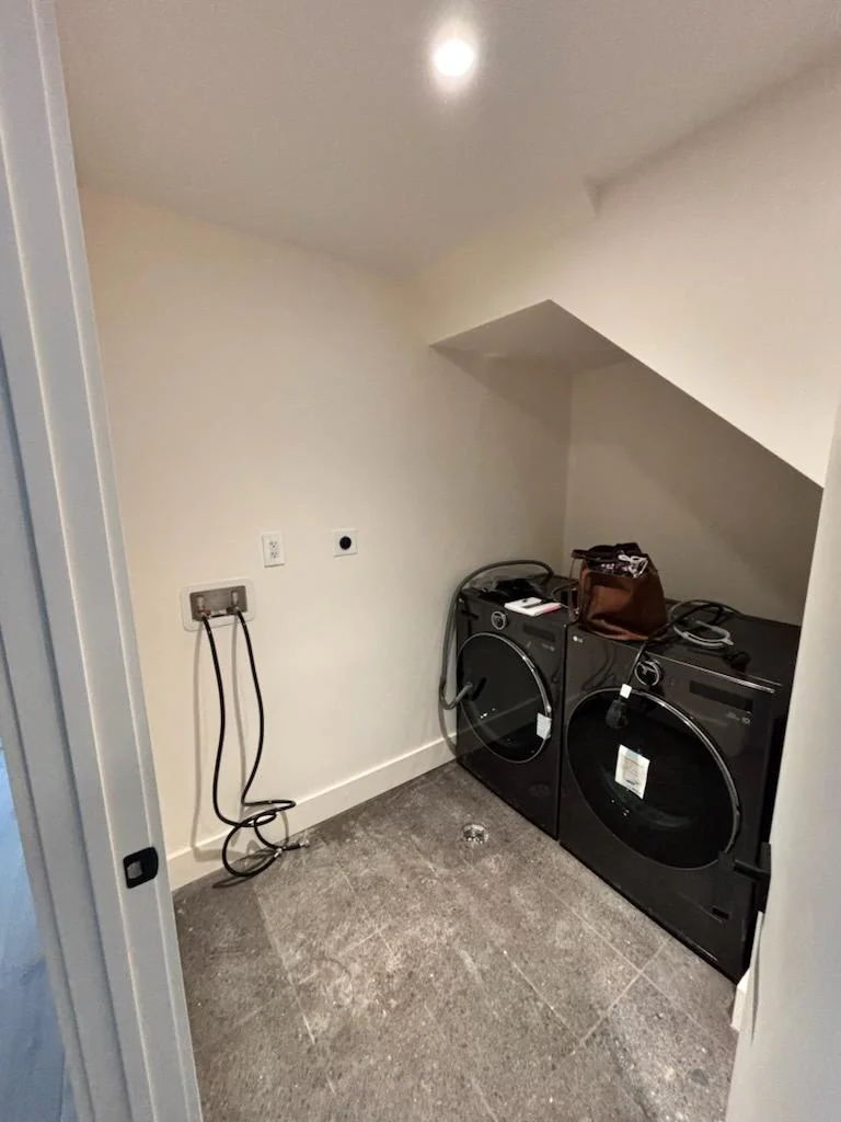 Before installation: laundry appliances and exposed connections in the room before the custom cabinets were fitted