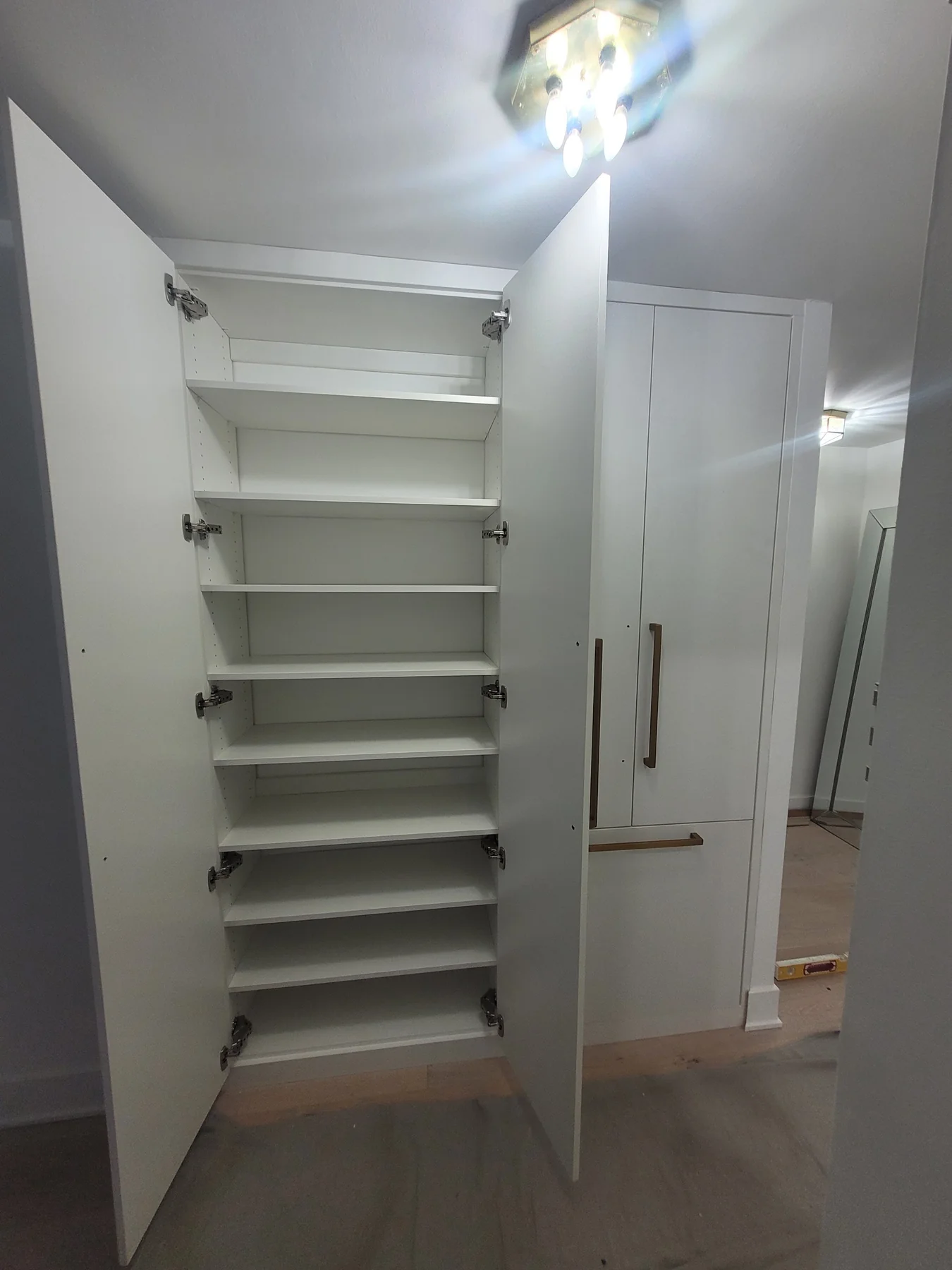 Wardrobe doors opened to reveal the tall shelving and pull-out storage inside