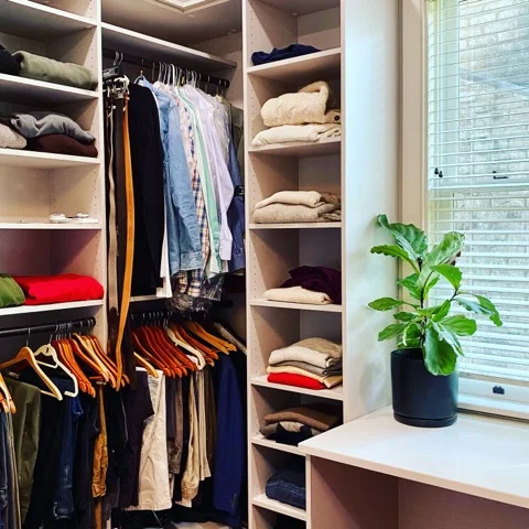 Window-side dressing table and corner shelves integrated into a fitted walk-in closet