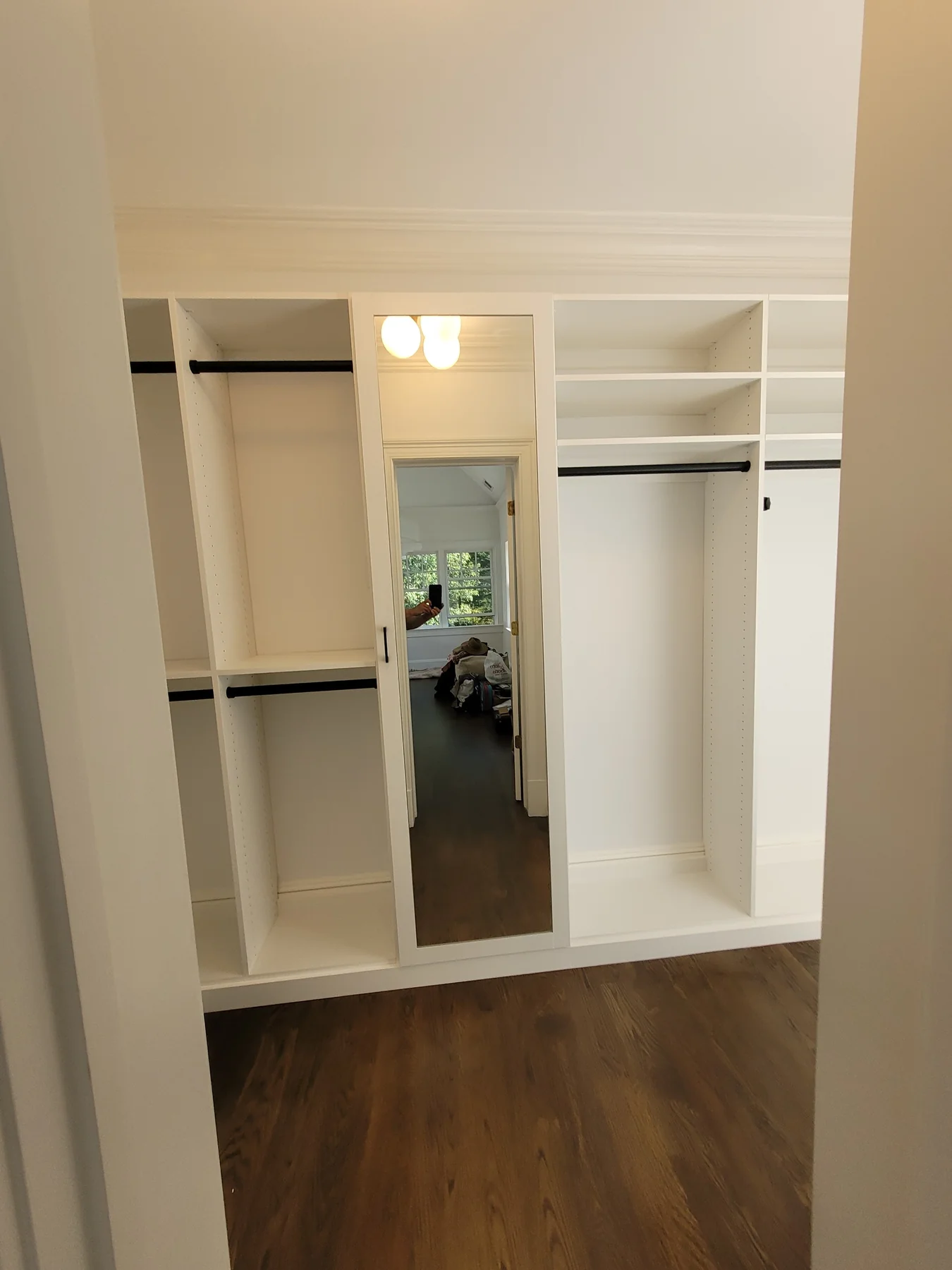White closet storage with a full-length mirror between open hanging sections