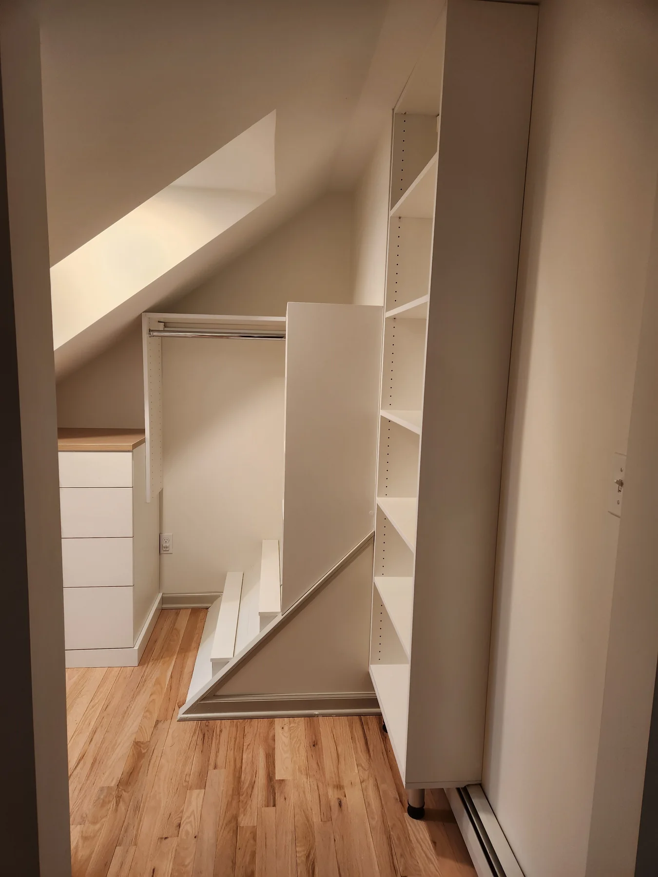 Closet storage fitted beneath a sloped ceiling with drawers, shelves and hanging space