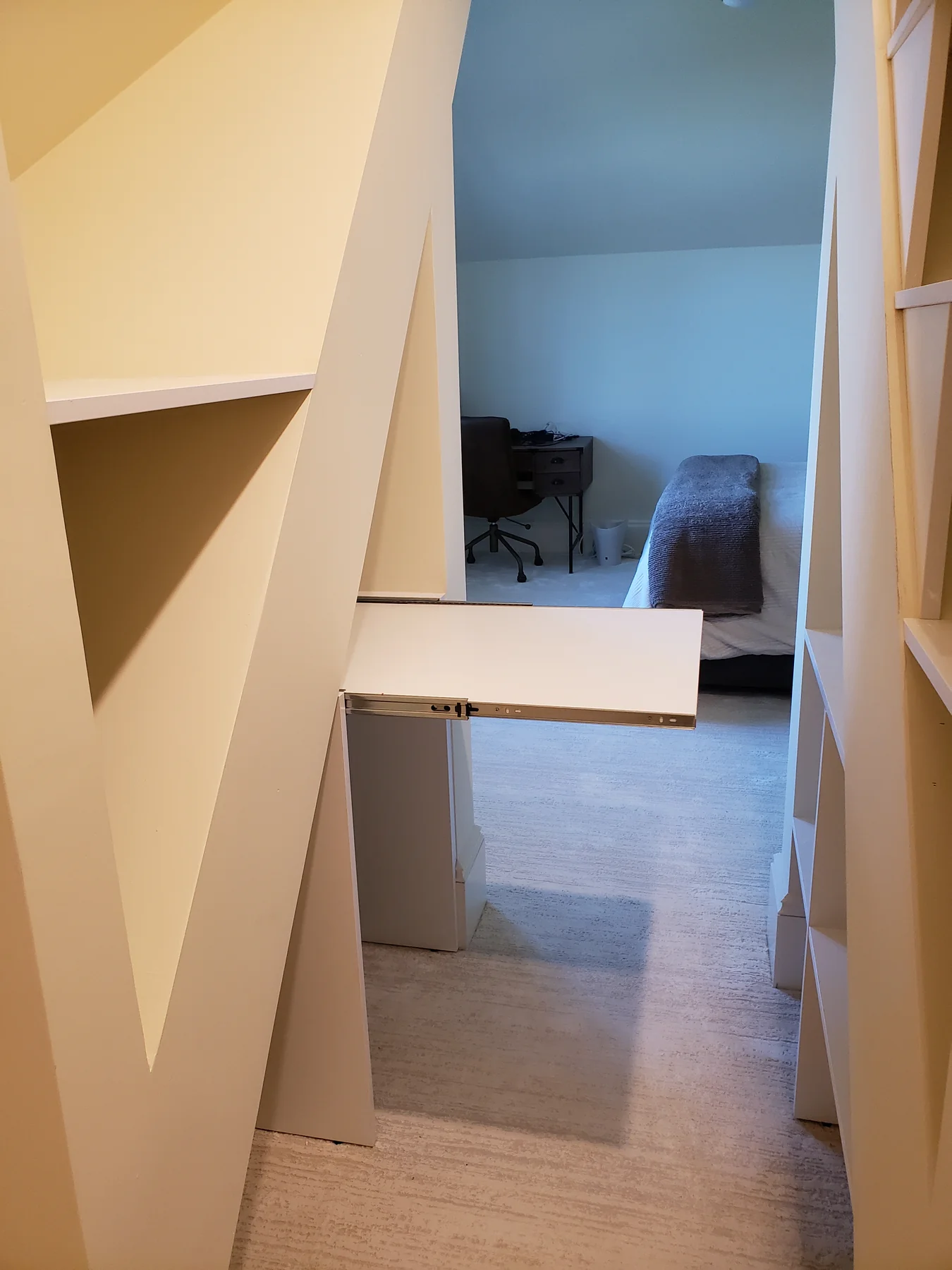 Pull-out shelf extending from custom storage beneath a sloped ceiling
