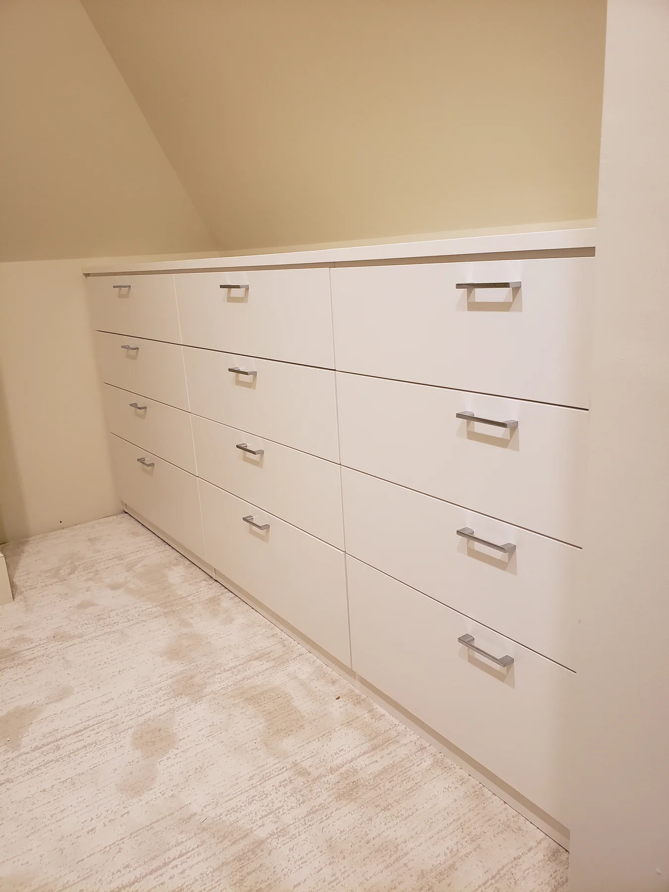 White drawer storage beneath an angled closet ceiling