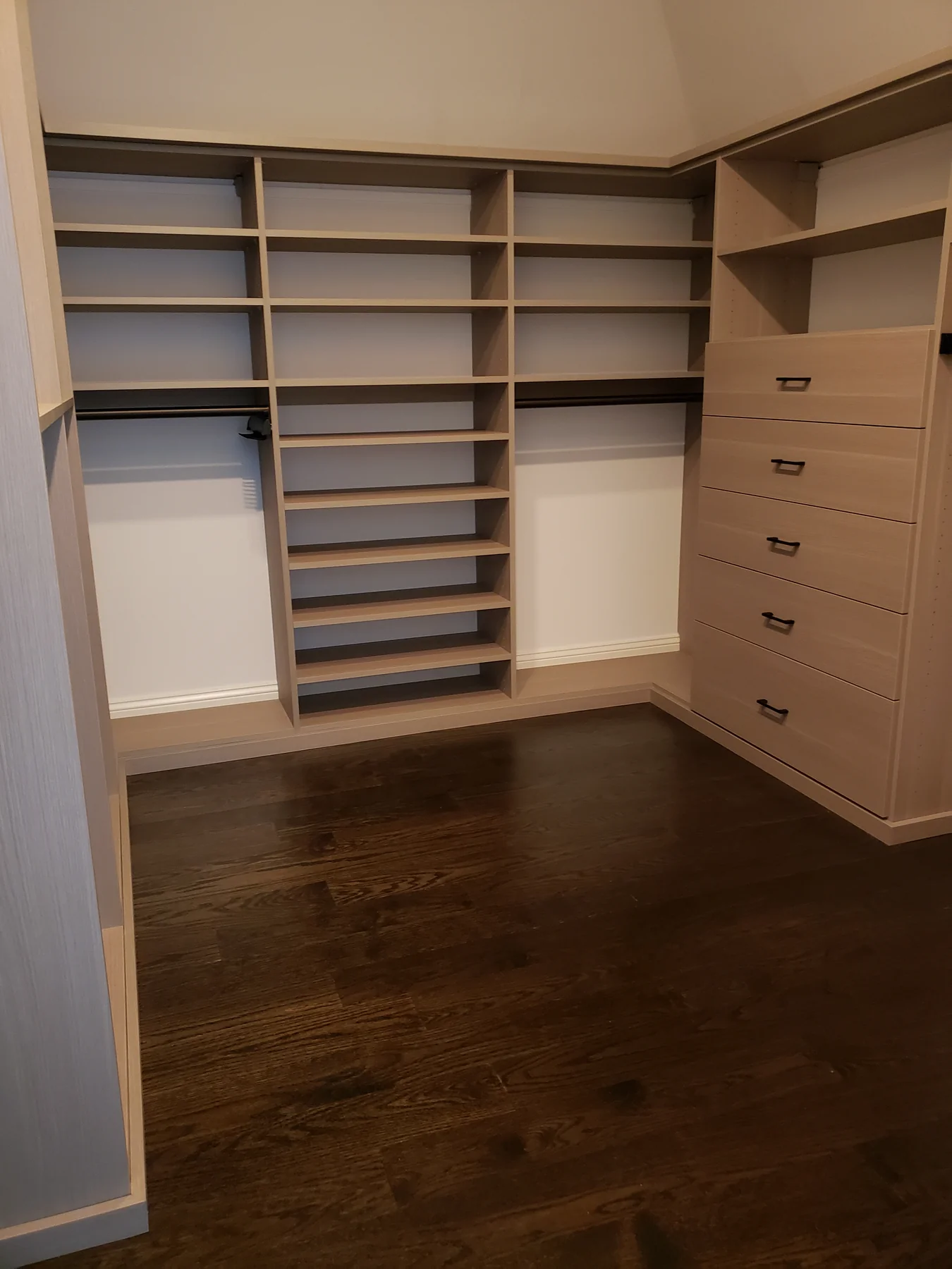 Warm wood-finish walk-in closet with adjustable shoe shelves and a drawer tower