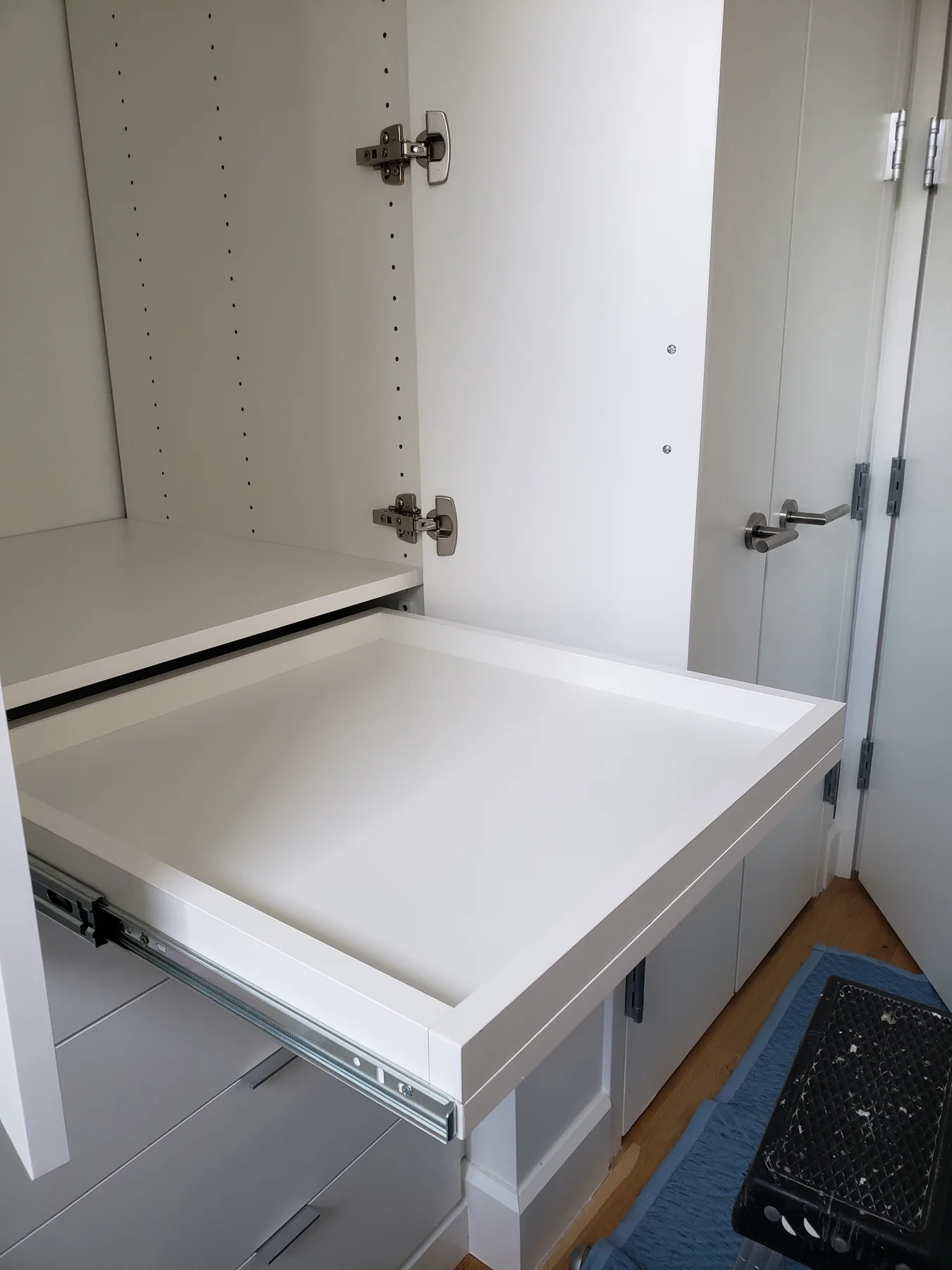 Extended pull-out tray inside a white wardrobe cabinet