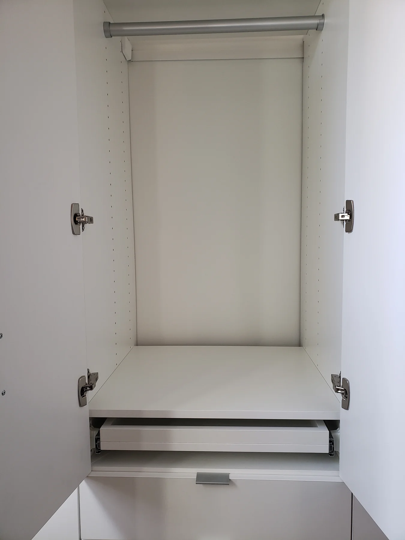 Open wardrobe interior with a hanging rail and pull-out storage
