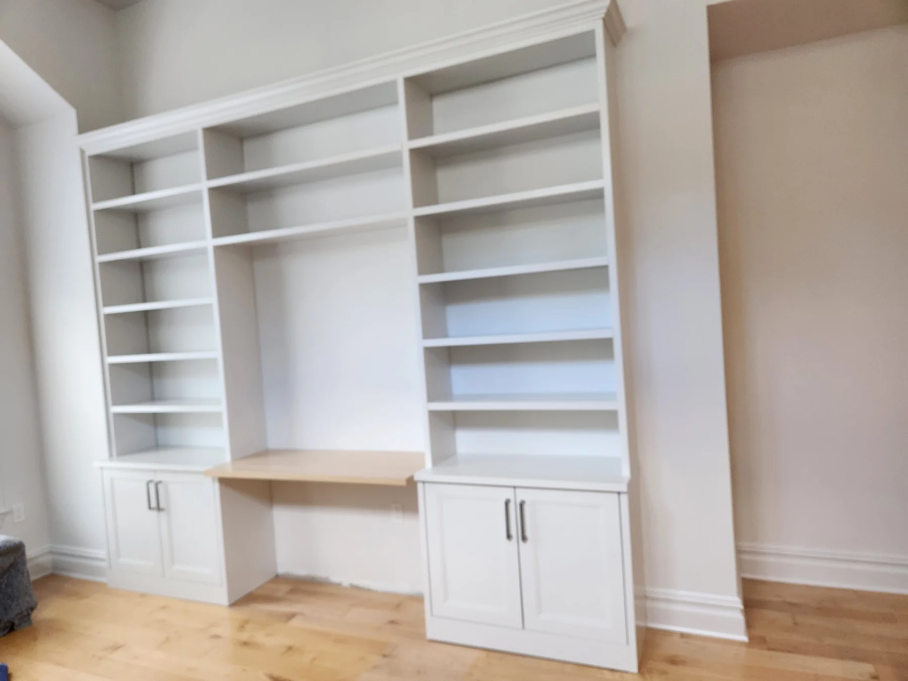 White built-in study wall with adjustable shelving, lower cupboards and a wood desk surface