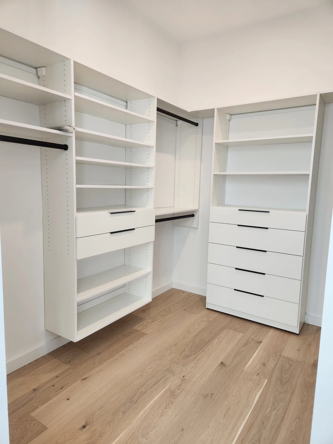 White walk-in closet with adjustable shelves, hanging rails and a drawer tower