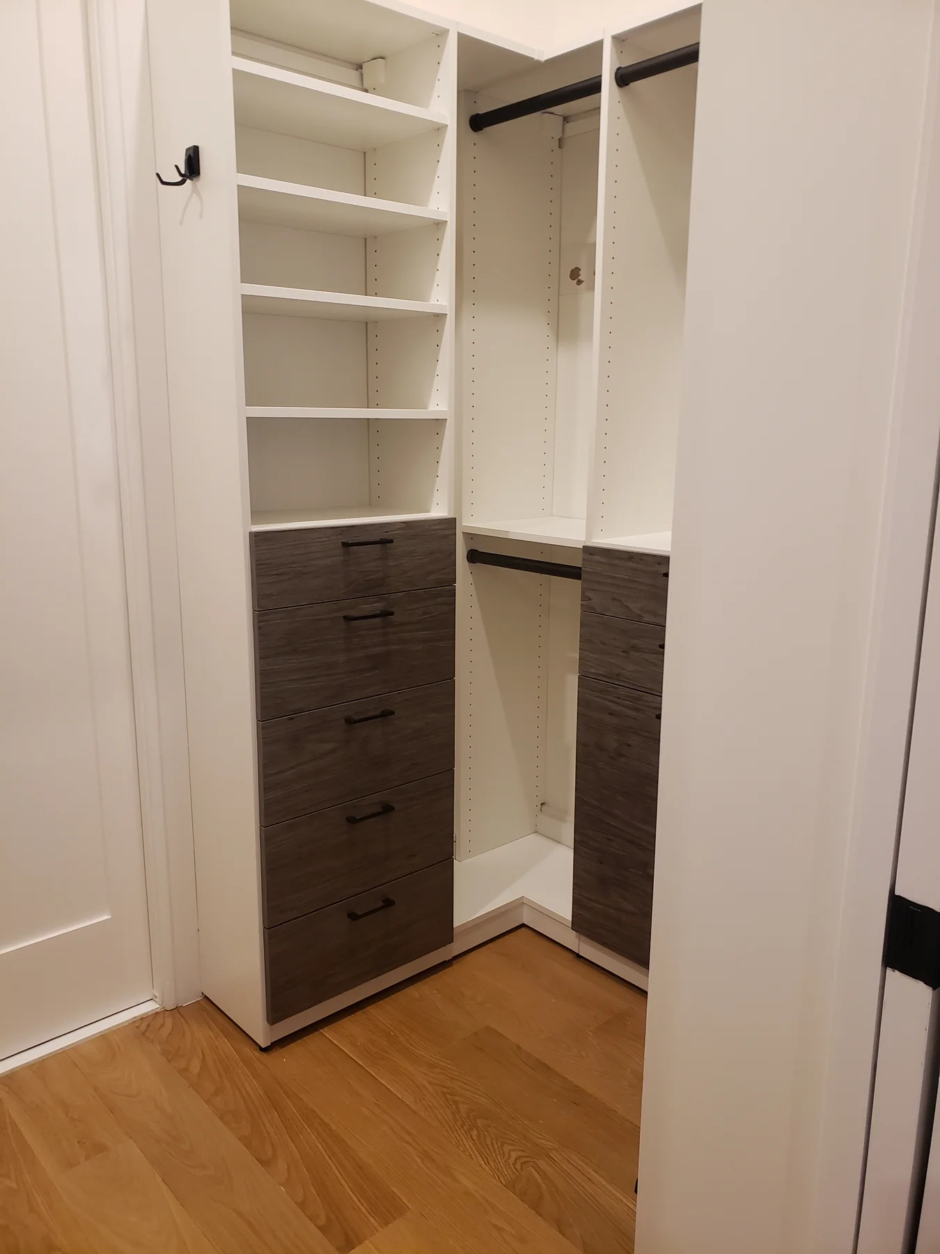 Two-tone closet with white shelves, hanging rails and a contrasting wood-finish drawer tower