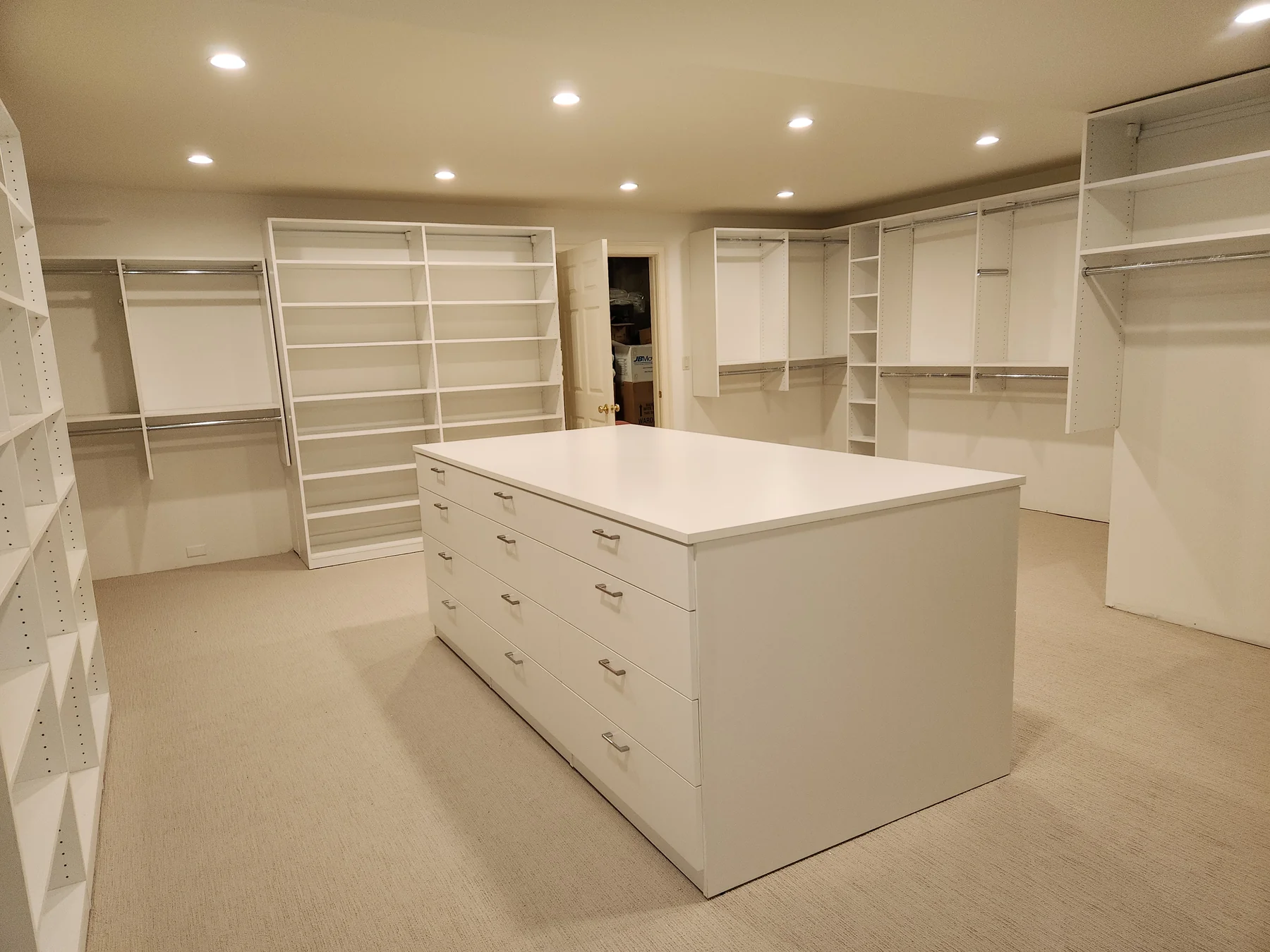 Opposite side of the freestanding white closet island with shelving behind