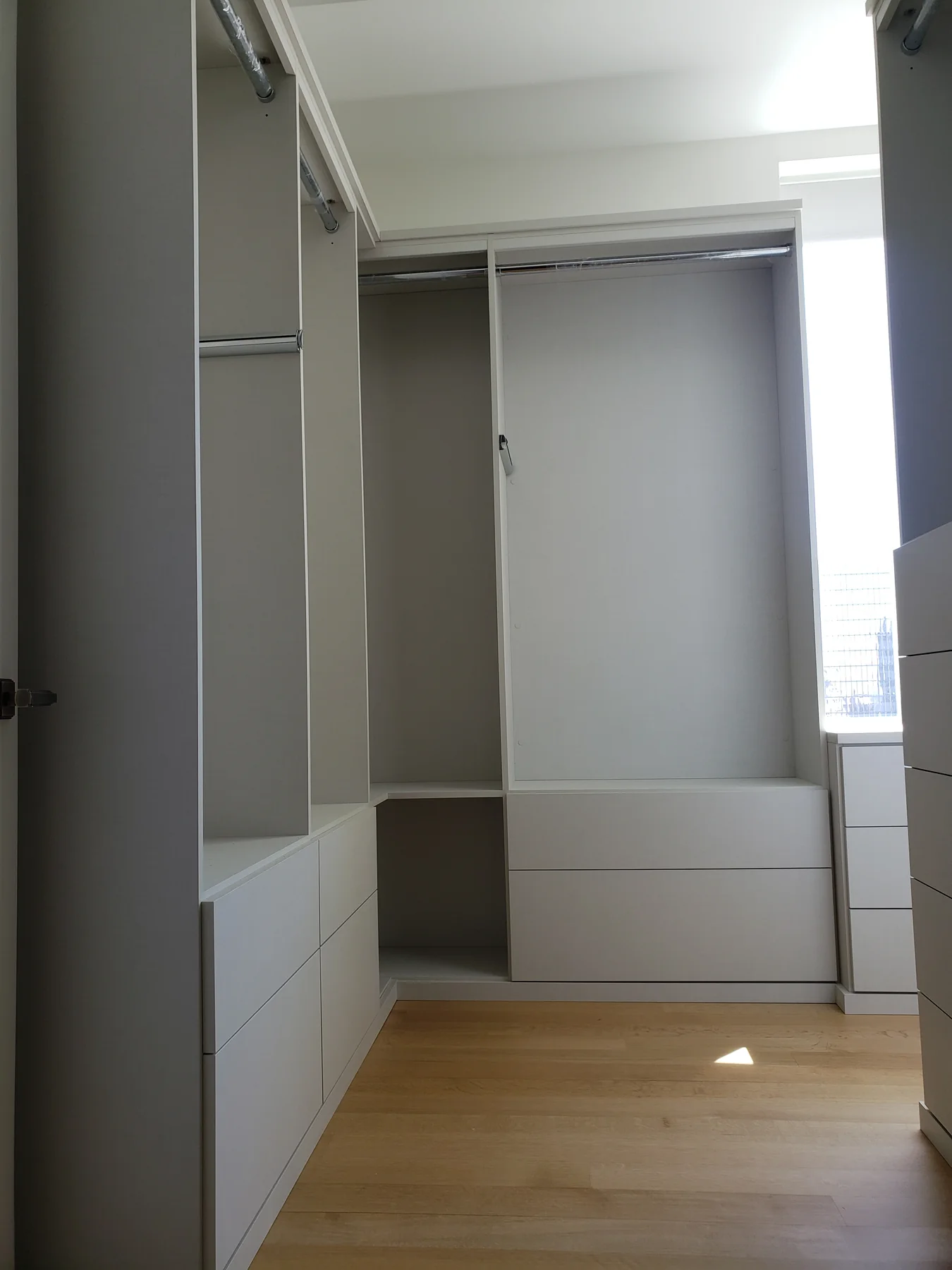 Closet hanging section and drawer unit beside a large window