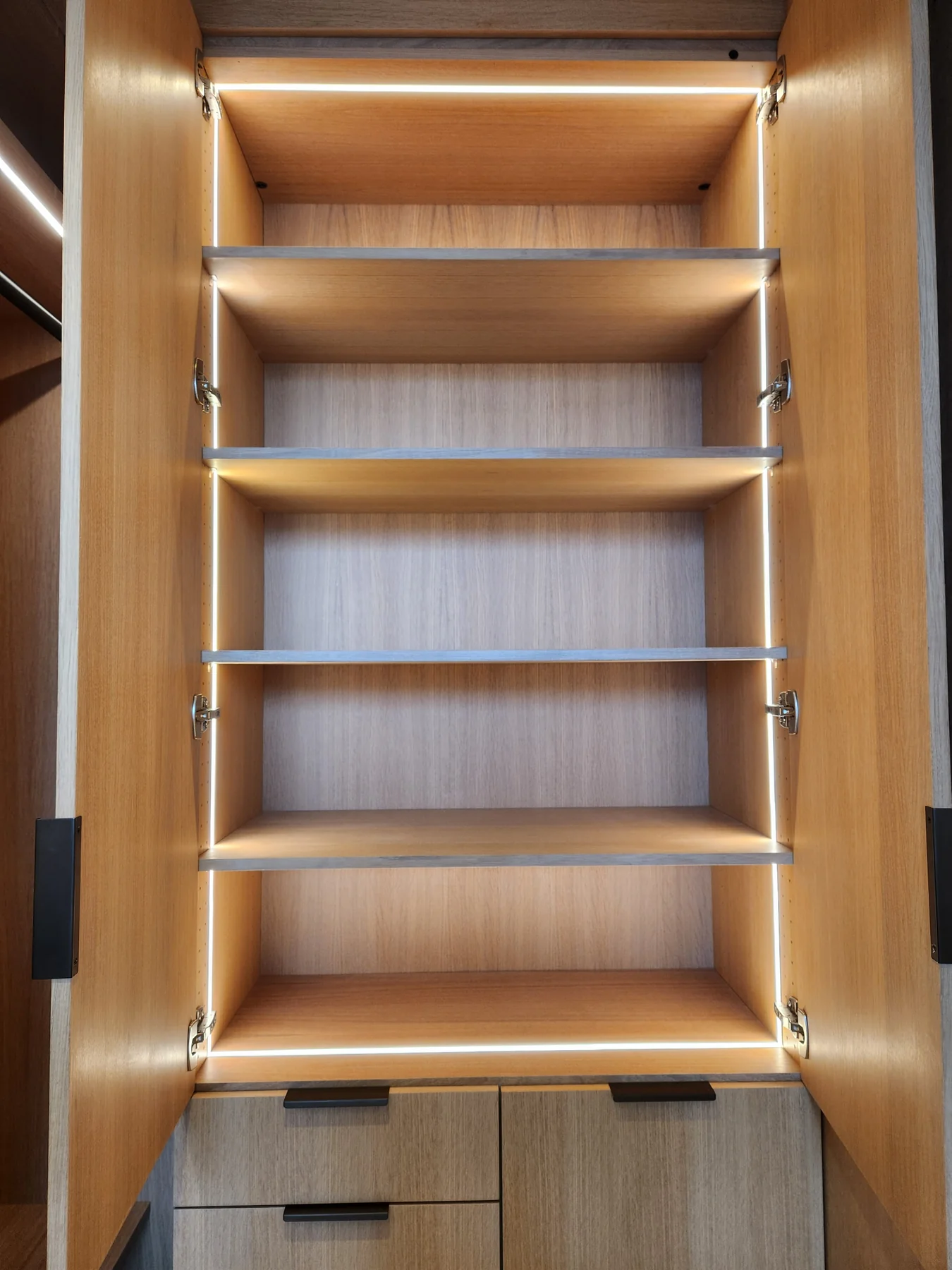 Closet shelving with integrated vertical lighting and drawers below